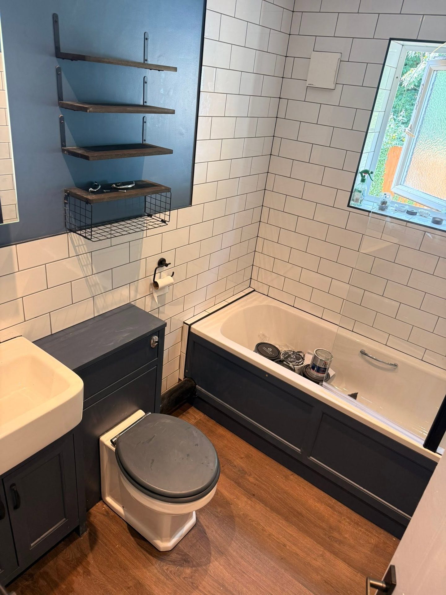 Finished bathroom with blue painted walls, white metro tiling and a black-framed shower screen