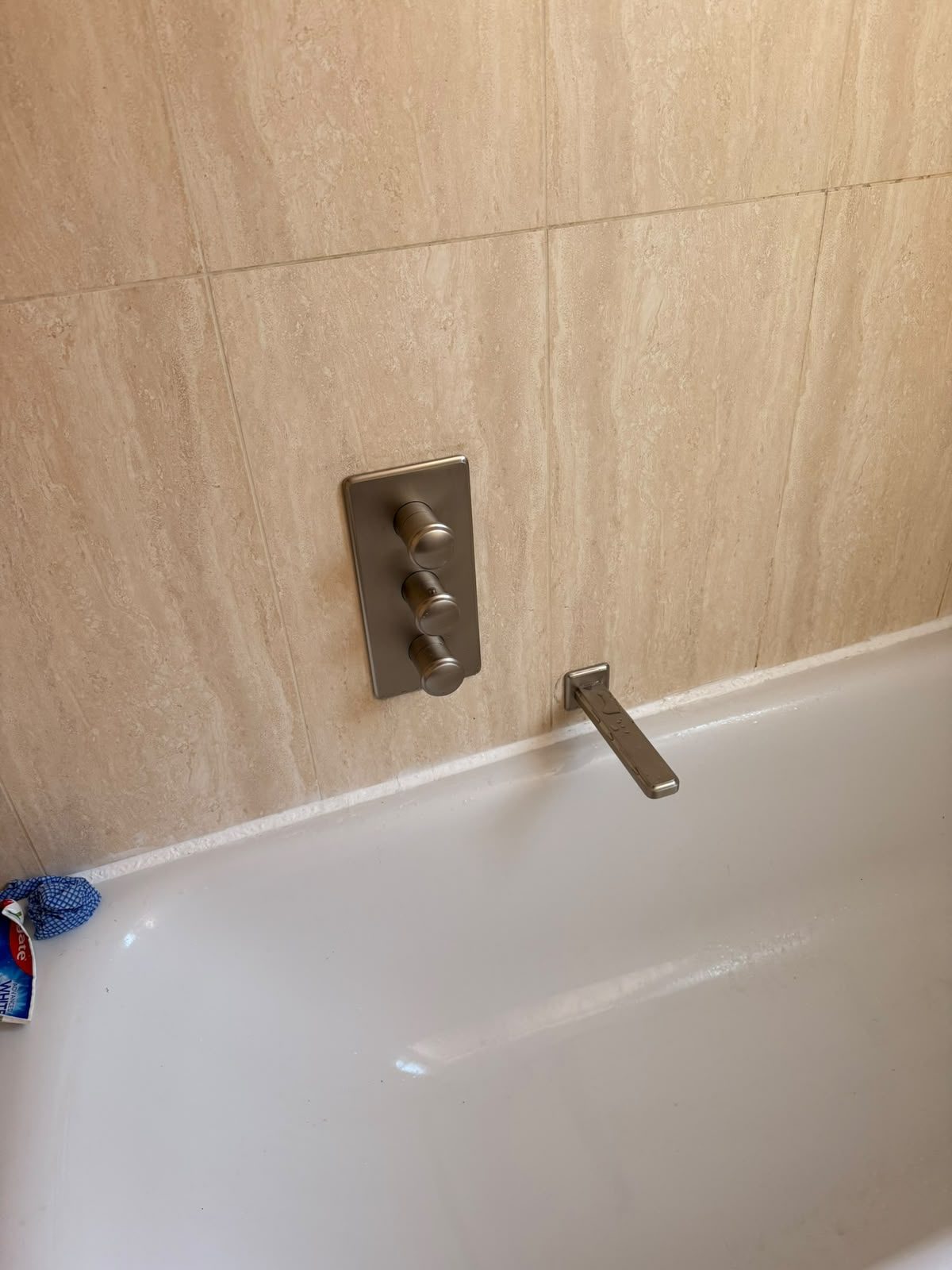 Wall-mounted chrome bath mixer tap with a minimalist spout, newly plumbed in during a bathroom installation