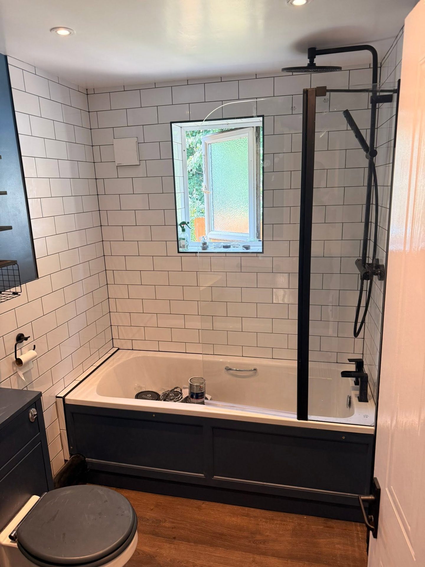 Bathroom refit with white metro wall tiles, a blue vanity unit and matt black shower fittings