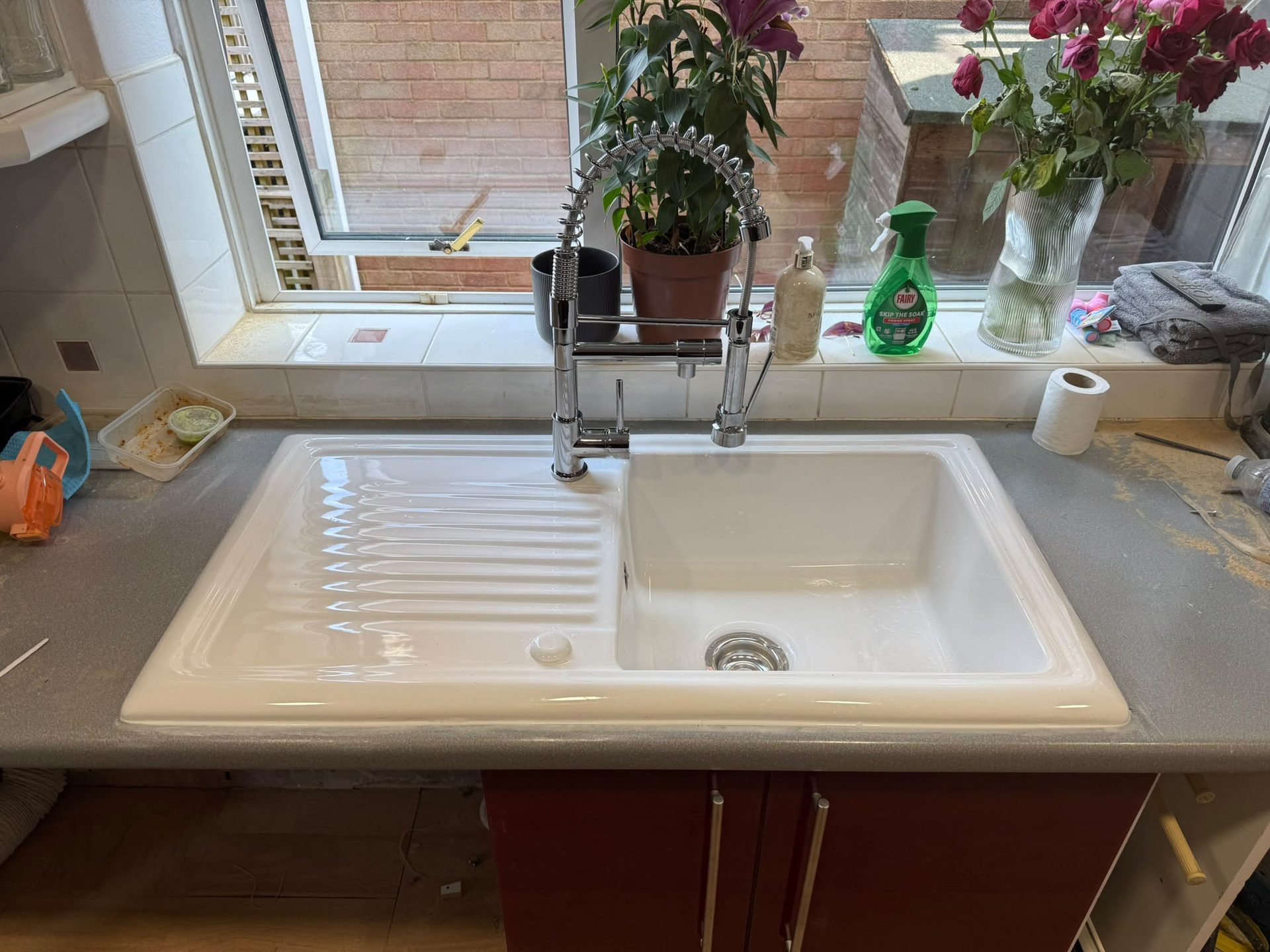 New kitchen sink and chrome pull-out spray mixer tap installed under a window