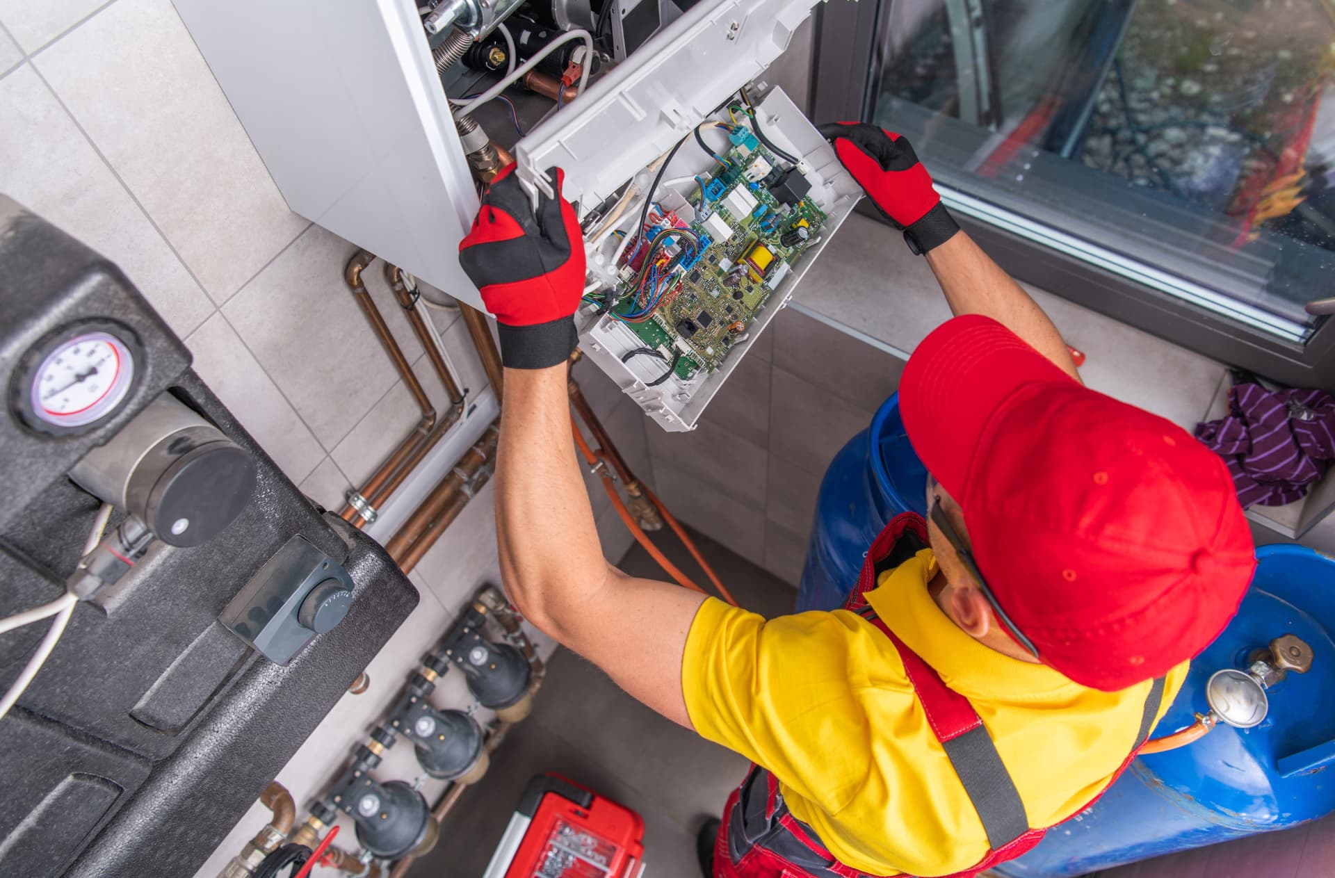 Gas Safe registered engineer working on the control board and gas pipework of a wall-mounted boiler