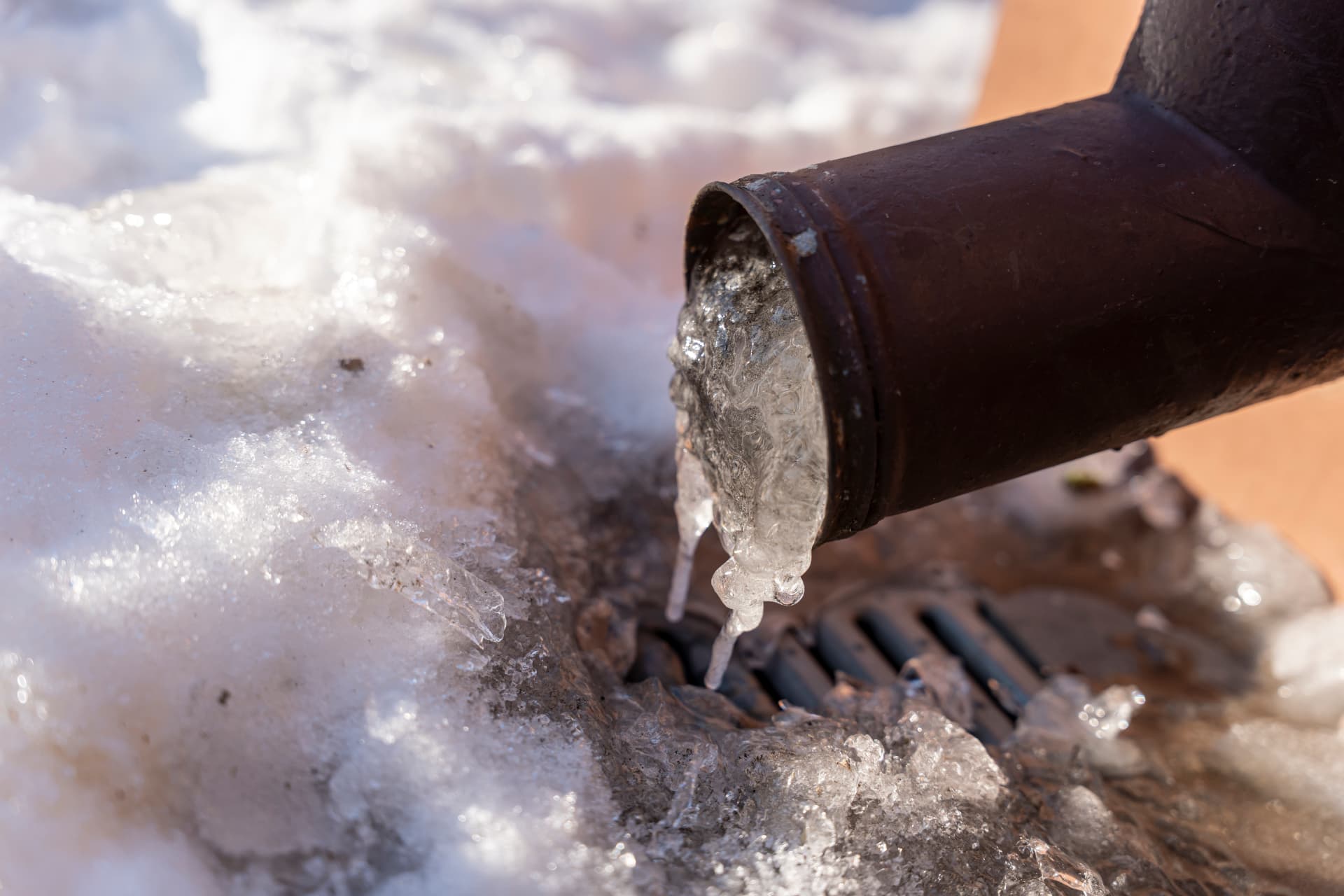 Blocked outside drain with an iced-up gully and frozen waste pipe outlet during a winter drainage call-out