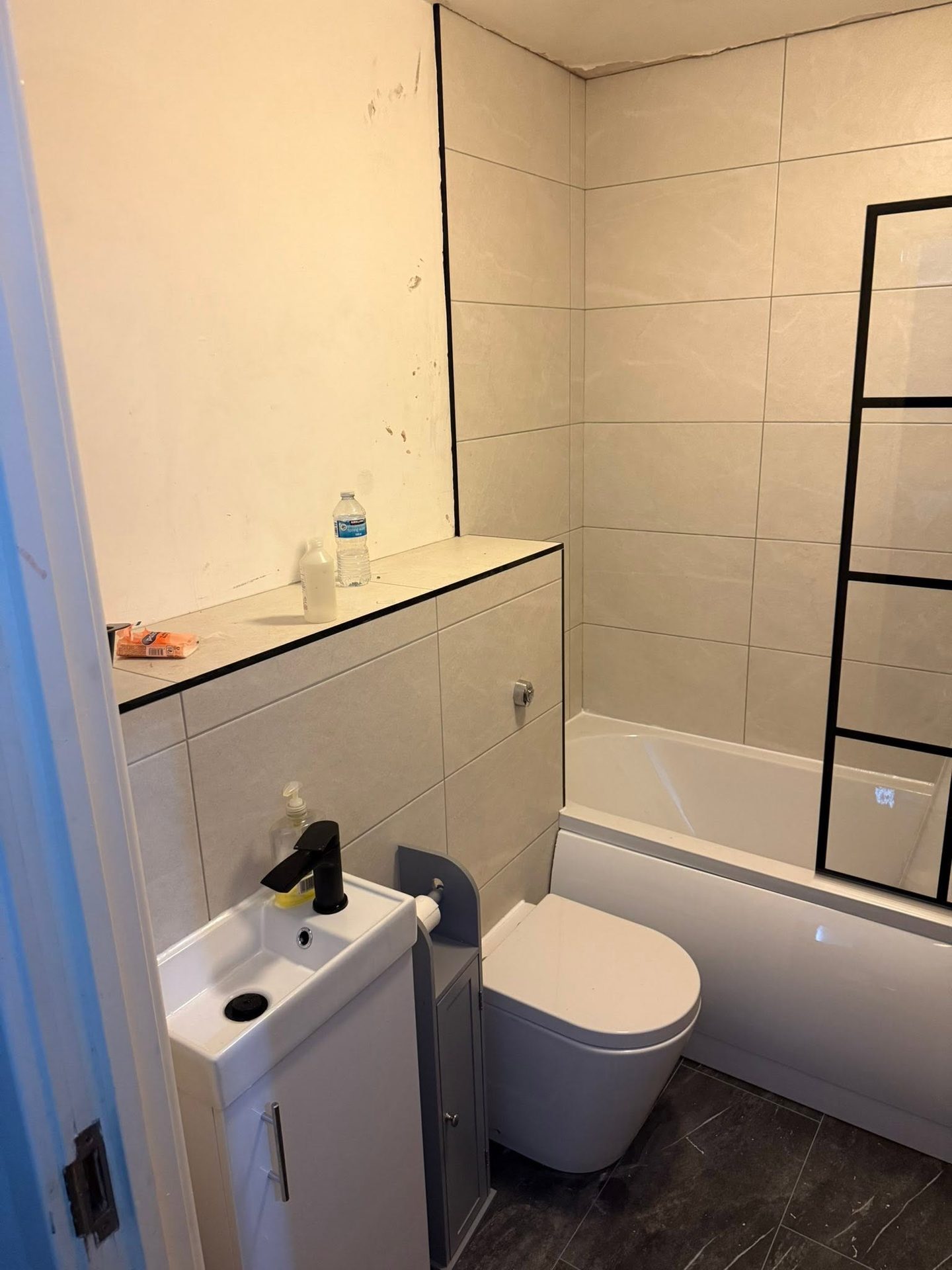 Compact bathroom installation with a small vanity unit, close-coupled toilet and marble-effect wall tiling